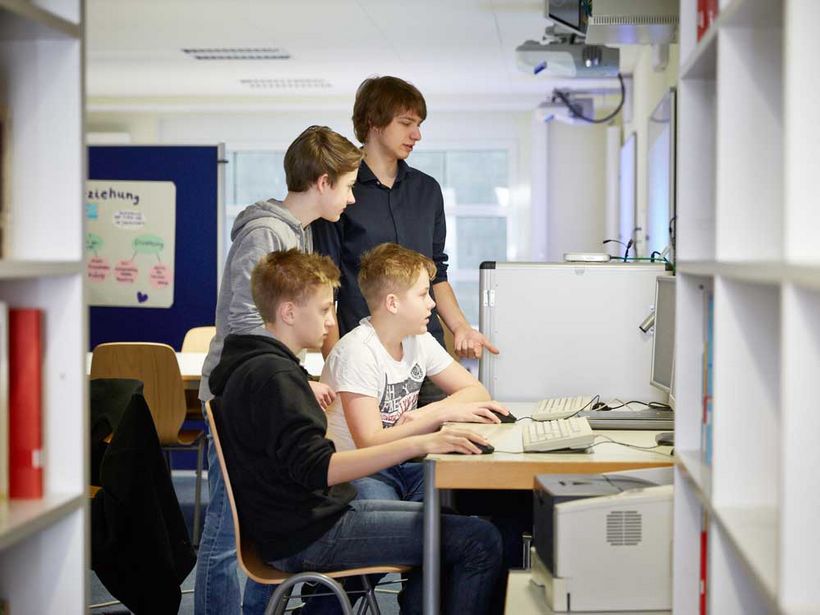 Vier Schüler versammelt an einem Computer