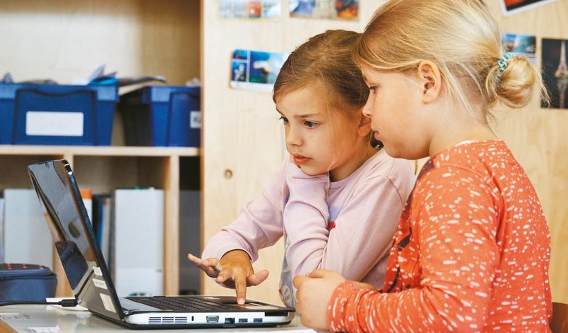 Zwei Mädchen bedienen zusammen einen Laptop