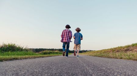 Ansicht von hinten, wie zwei Jungen eine Straße entlang laufen