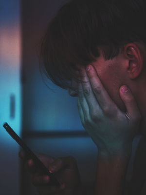 Symbolbild: Teenager guckt verzweifelt auf sein Smartphone