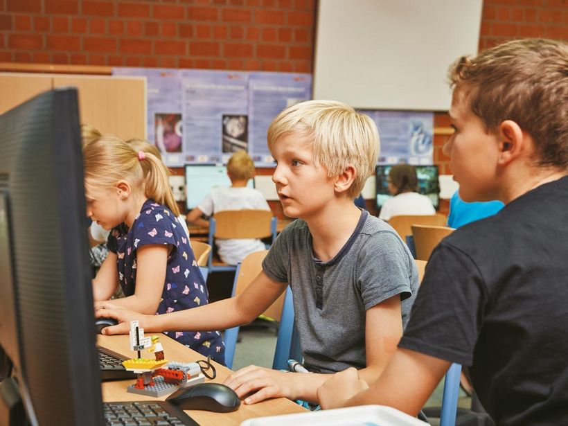 Grundschüler sitzen an Computern und pragrammieren