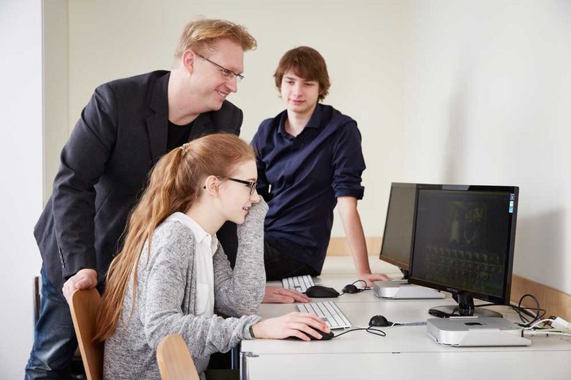 Lehrer Michael Schwarz und Medien-Bufdi Lars Eggers helfen einer Schülerin am Computer