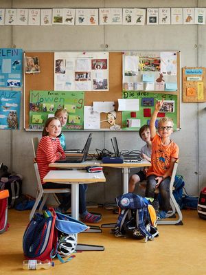 Vier Grundschüler sitzen mit Laptops an einem Tisch