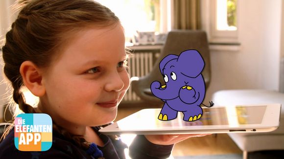 Ein Mädchen hält ein Tablet in der Hand, darauf steht der kleiner blaue Elefant