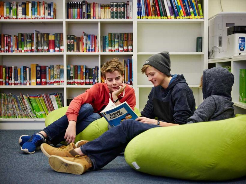Zwei Schüler sitzen auf Sitzsäcken und lesen ein Buch zusammen