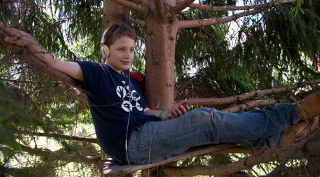 Ein Junge sitzt auf einem Baum und trägt Kopfhörer