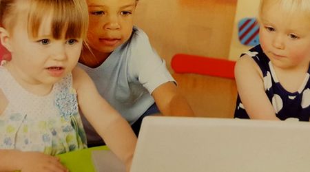 Drei kleine Kinder sitzen vor einem Laptop