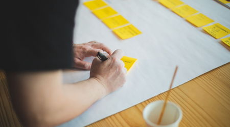 Eine Person schreibt auf einen Post-It